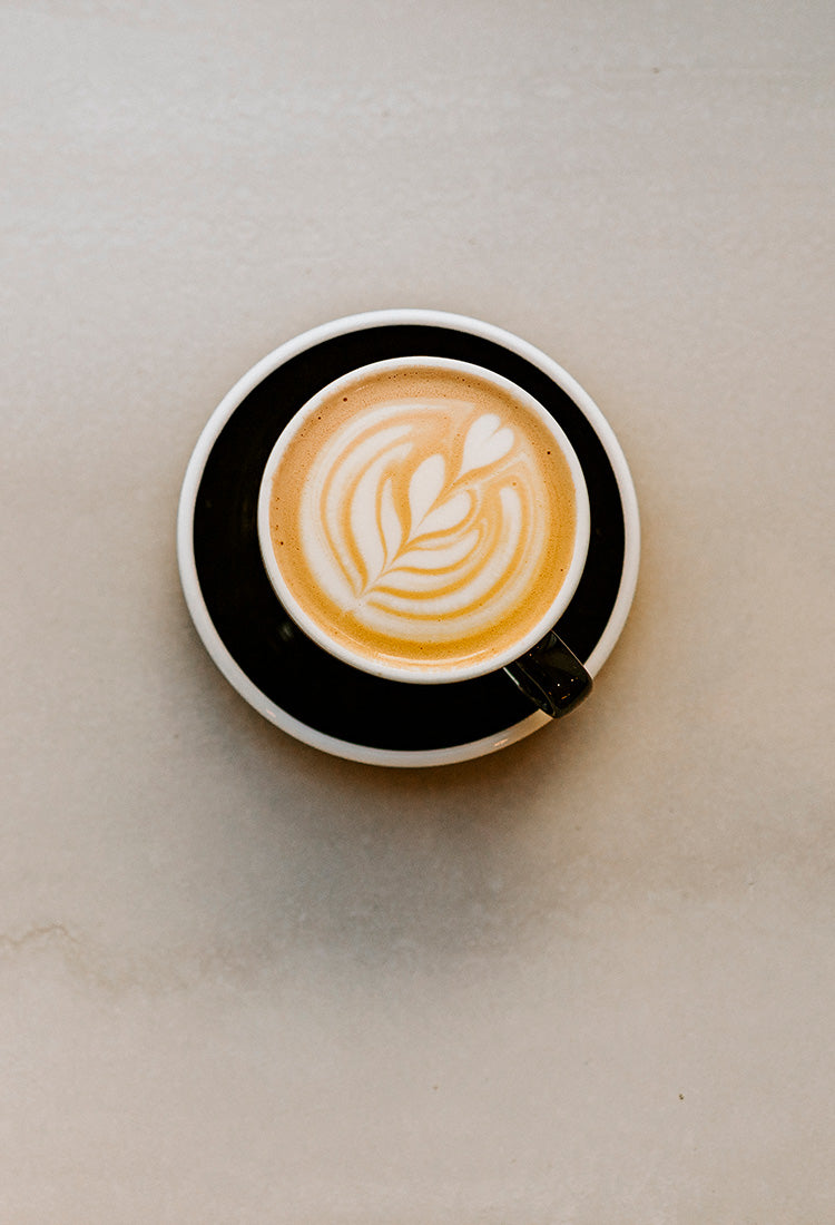 Tasse ERNST Kaffee mit Latte Art auf beigem Hintergrund